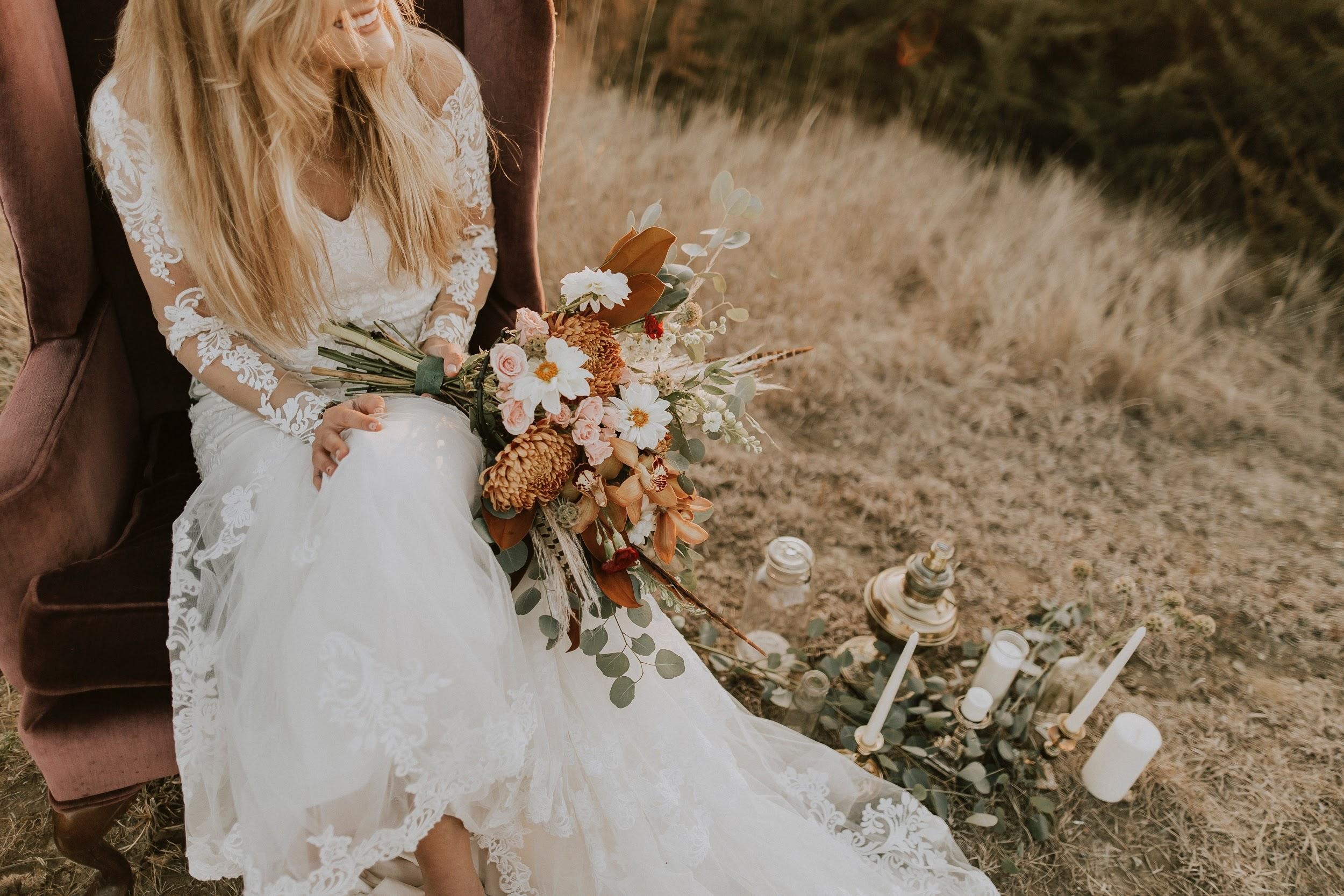 Woman in a wedding dress with her bouquet sitting on the grass