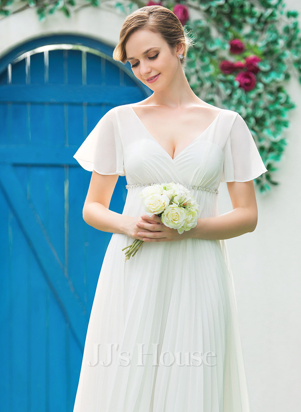 Model in regal empire wedding dress holding a mini bouquet