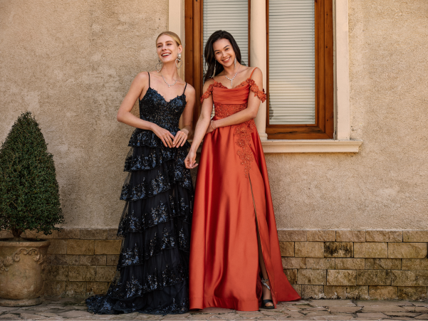 two models in long dresses, one in black and the other in orange.