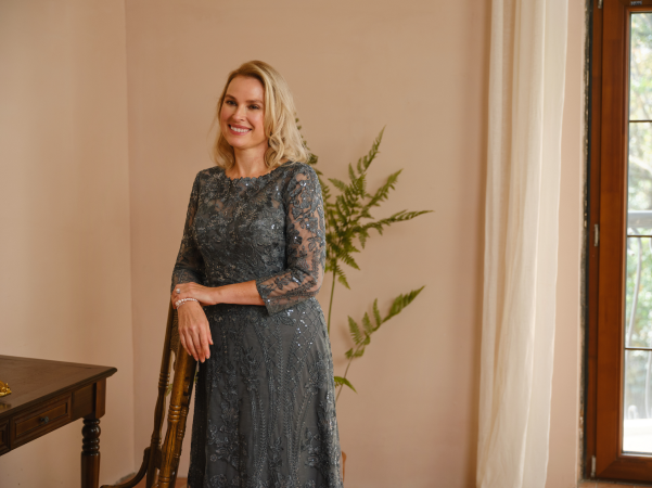 Mother in a grey dress leaning on a chair